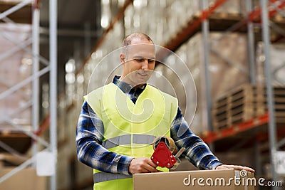 Man in safety vest packing box at warehouse Stock Photo