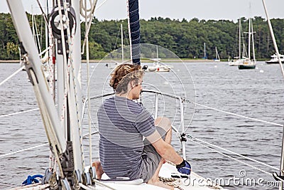 Man on sailboat tying a rope to cleat Stock Photo