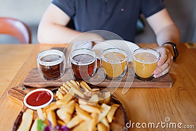 Man sampling variety of seasonal craft beer in pub. Beer samplers in small glasses individually placed in holes Stock Photo