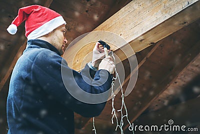 Man with santa hat decorating house outdoor carport with christmas light garland Stock Photo