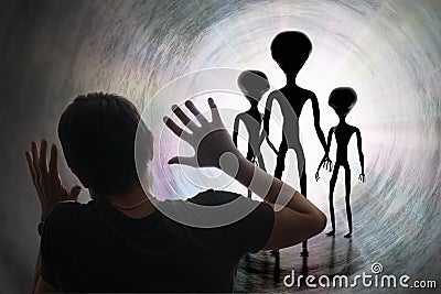 Man is scared of silhouettes of aliens in tunnel. Abduction and kidnapping by aliens concept. Stock Photo