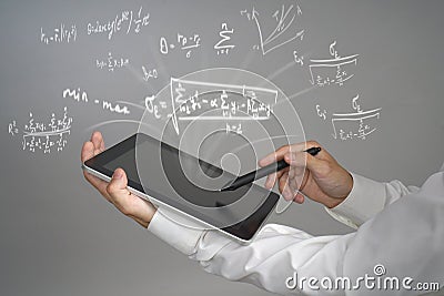 Man scientist or student holding tablet PC and working with various high school maths and science formulas. Stock Photo