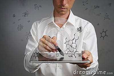 Man scientist with tablet pc and stylus or pen working with chemical formulas on gray background. Stock Photo