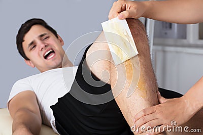 Therapist Waxing Man`s Leg With Wax Strip Stock Photo