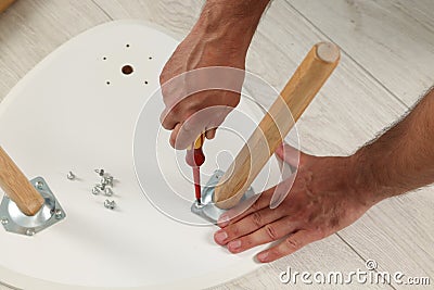 Man with screwdriver assembling stool on floor, above view Stock Photo