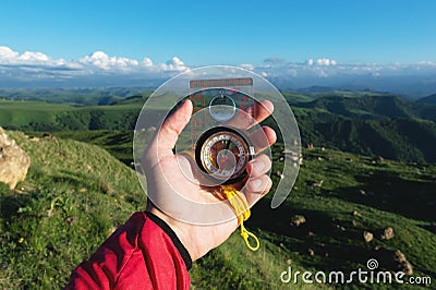 Man searching direction with a compass in his hand in the summer mountains point of view. Direction Search Stock Photo