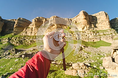 Man searching direction with a compass in his hand in the summer mountains point of view. Direction Search Stock Photo