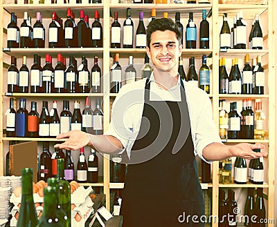 Man seller wearing uniform standing in shop with wine Stock Photo