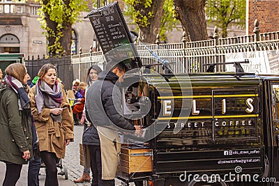 Man is selling fresh cappucino, espresso coffee and tea in a mobile coffee shop in a small car to female cutomers. Editorial Stock Photo