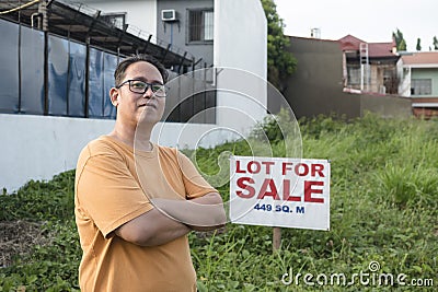 A man selling his undeveloped property inside a residential sudivision. An empty lot with a for sale sign Stock Photo