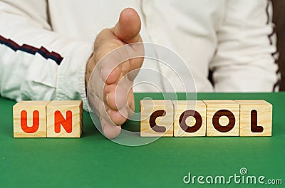 A man separates the cubes with the inscription - UNCOOL or COOL Stock Photo