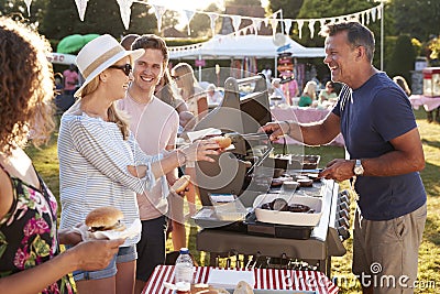 Man Serving On Barbeque Stall At Summer Garden Fete Stock Photo