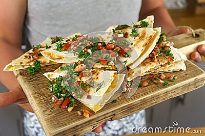 Man serving Mexican chicken quesadillas on wooden board Stock Photo