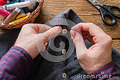 Man sews a button to his shirt Stock Photo