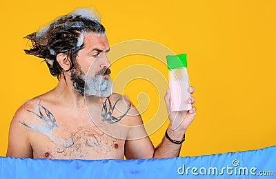 Man with shampoo bottle. Bearded male washing hair. Bath time. Guy with foam on head. Copy space. Stock Photo