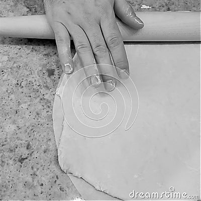 Man shapes pizza dough crust with rolling pin on home granite countertop Stock Photo