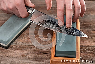 Man sharpening a chef`s knife with Damascus steel Stock Photo