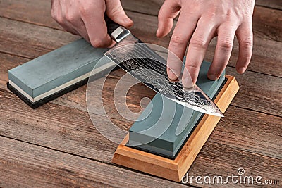 Man sharpening a Japanese chef`s knife with a wet whetstone Stock Photo