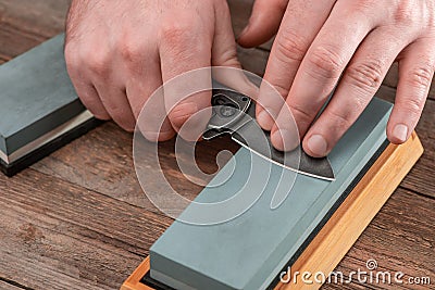 Man sharpening a pocket knife using a whetstone Stock Photo