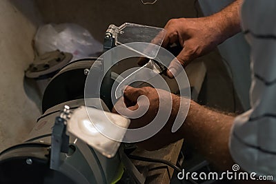 Man sharpens a knife on an electric grindstone Stock Photo