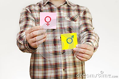 A man in a shirt holds stickers with the image of the gender sign of a man and a woman. Sexual education Stock Photo