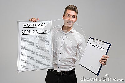 Young man holding poster with mortgage application and contract isolated on light background Stock Photo