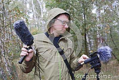 The man with Shotgun Condenser Microphone and headphones is recording the sounds of nature. Stock Photo