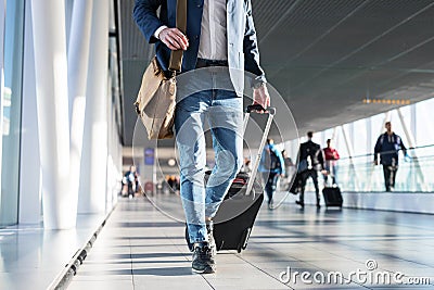 Man with shoulder bag and hand luggage walking in airport terminal Stock Photo