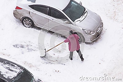 Man shoveling snow after snowfall on road, parking near car Stock Photo