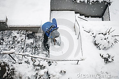 Man shovelling and clear the snow, winter work on premises with snow pusher Stock Photo