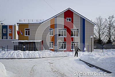 Man is shovelling snow in front of the building of Lesovichok nursery school in Ordzhonikidze street of Balashikha, Russia. Editorial Stock Photo