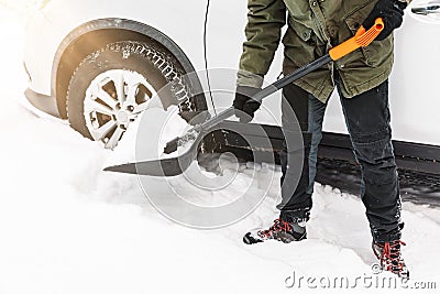 Man is shovelling snow near the car. Winter shoveling. Removing snow after blizzard Stock Photo