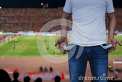 Man showing his empty pockets on blurred soccer stadium Stock Photo