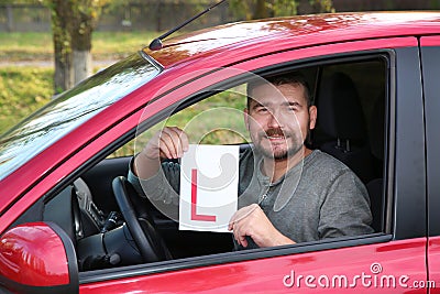 Man showing learner driver sign from new car. Stock Photo