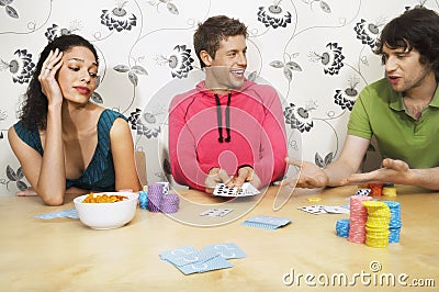 Man Showing Winning Hand To Friends While Playing Cards Stock Photo