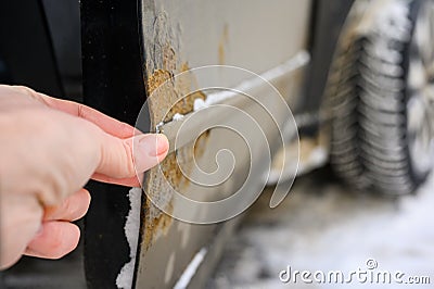 A man shows rust on a car door from winter reagents. Stock Photo