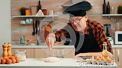 Man sieving flour over dough on table Stock Photo