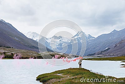 Man with signal fire on background of mountain lake Stock Photo