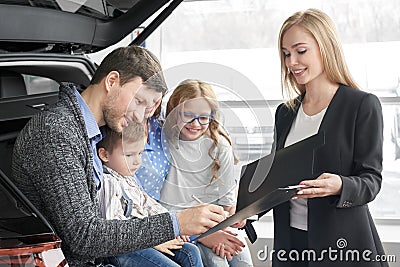 Man signing document of automobile purchase, happy family. Stock Photo