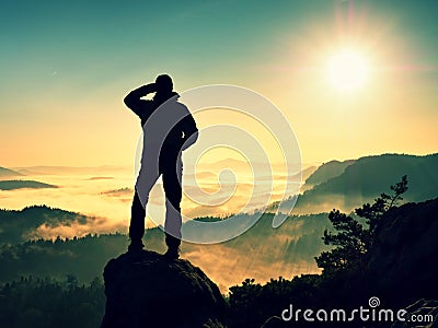 Man silhouette climbing high on cliff. Hiker climbed up to peak enjoy view. Stock Photo