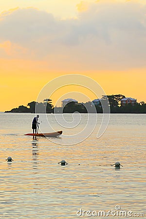 Man silhouette rowing standng on a boat at sunset time. Stock Photo