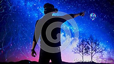 Man silhouette wearing virtual reality glasses in front of digital screen playing with cyber graphic space background Stock Photo