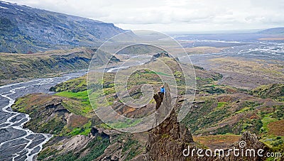 Man siting on a ledge of a mountain, enjoying the beautiful view valley in Thorsmork Stock Photo