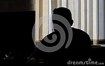 Man sits in the office at the computer. only silhouette. he looks at the cameras on the monitor Stock Photo