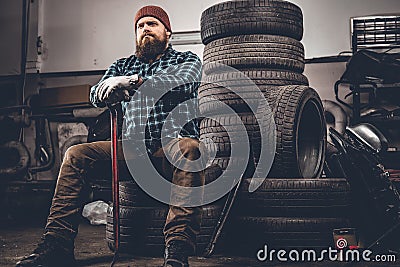 A man sits on an old tire in a garage. Stock Photo