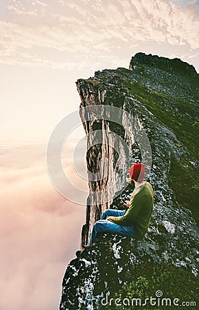 Man sitting alone on the edge mountain ridge above clouds Stock Photo