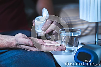 Man sitting on bed about to take sleeping pill or night medicine Stock Photo