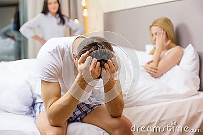 Man sitting on the bed with two women on the back Stock Photo