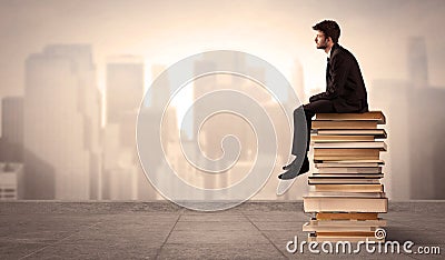 Man sitting on books in the city Stock Photo