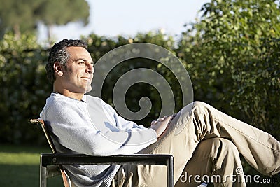 Man Sitting On Chair In Backyard Stock Photo